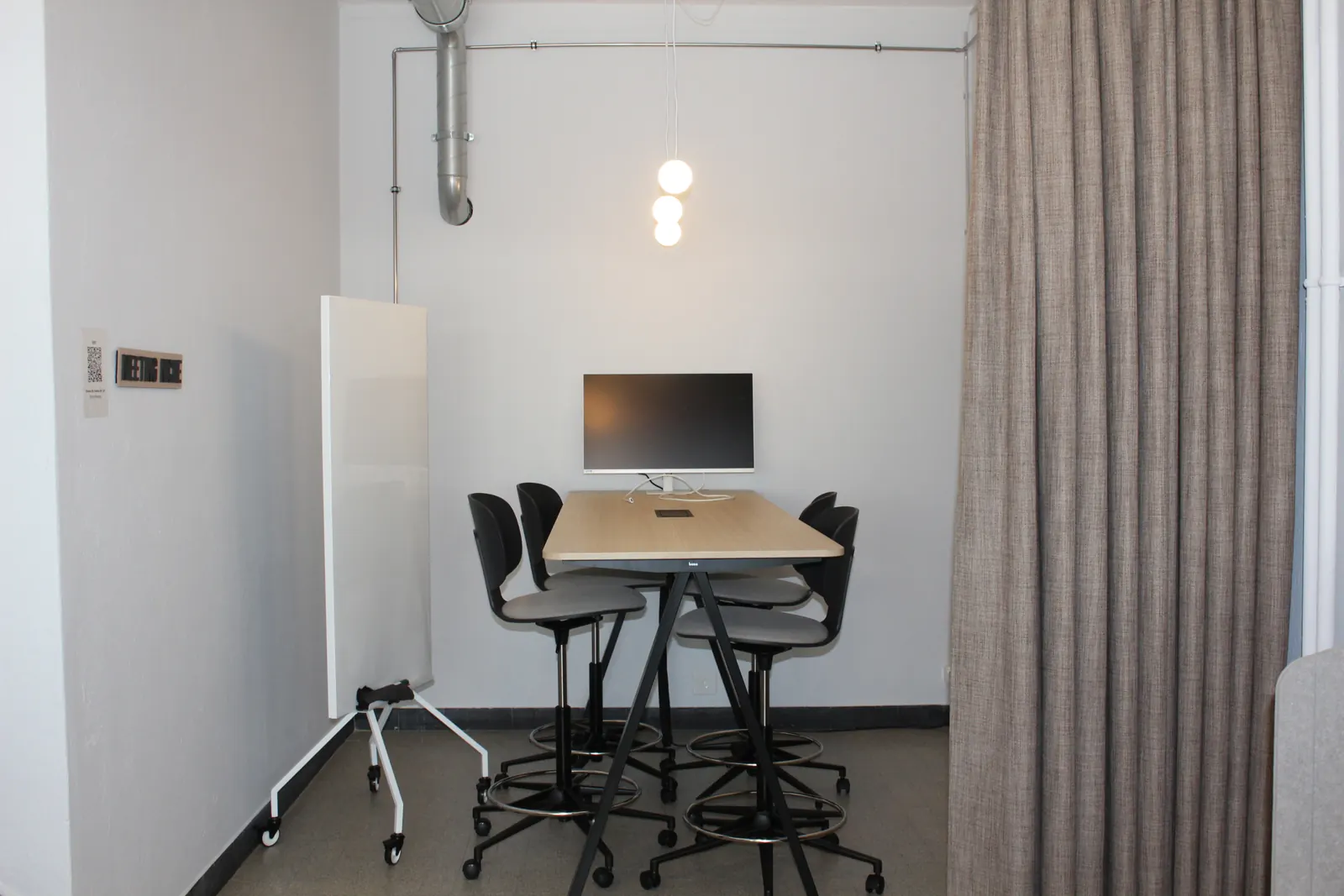 Meeting nook with a high table, four chairs, a screen and a whiteboard