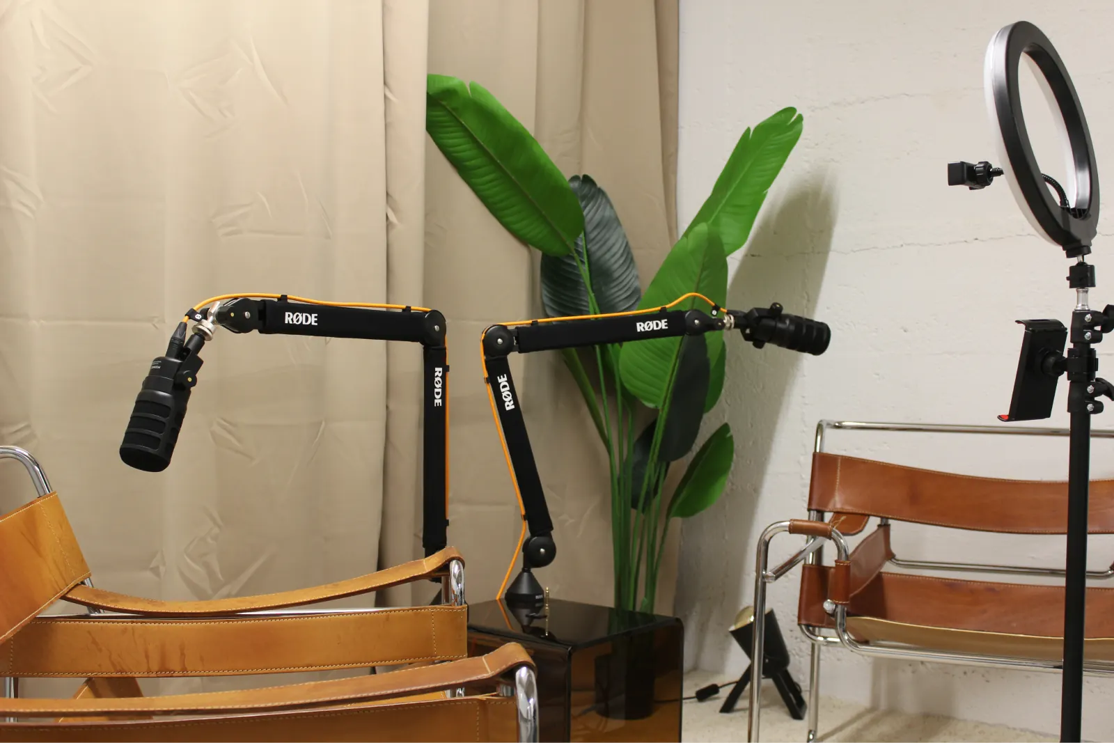 Podcast setup with two microphones, leather chairs and a ring light